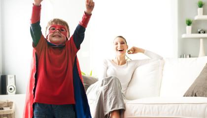 Kind im Superheldenkostüm vor seiner Mutter